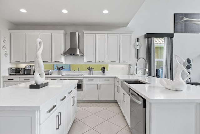 kitchen featuring wall chimney exhaust hood, a peninsula, stainless steel appliances, white cabinetry, and a sink