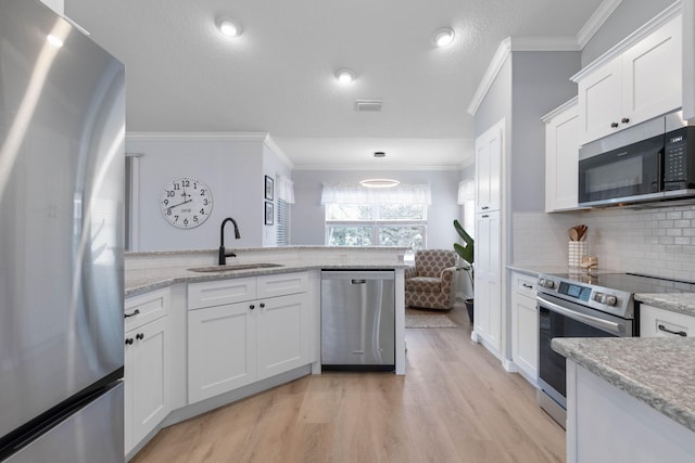 kitchen with crown molding, stainless steel appliances, light wood-style flooring, white cabinets, and a sink