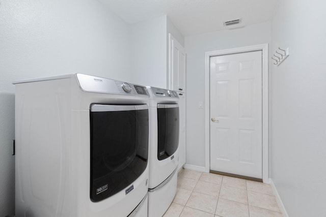 laundry area with light tile patterned floors, independent washer and dryer, visible vents, and baseboards