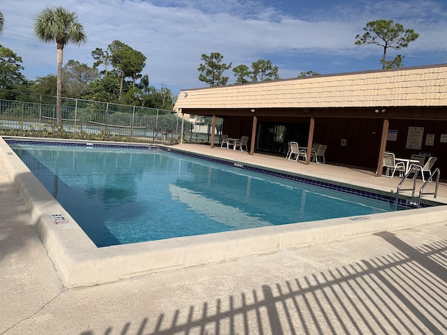 community pool with fence and a patio