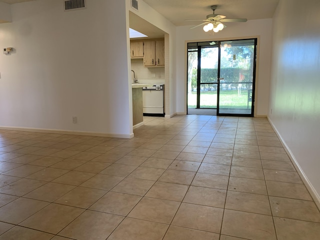 unfurnished room with light tile patterned floors, visible vents, a ceiling fan, and baseboards