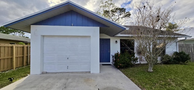 ranch-style home with a garage, driveway, fence, board and batten siding, and stucco siding