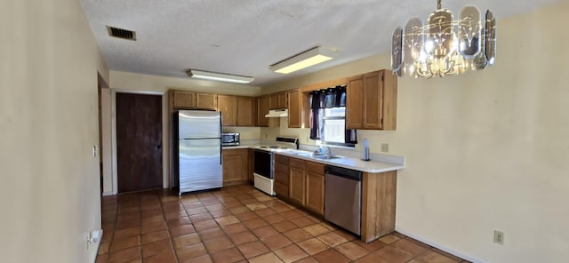 kitchen with visible vents, an inviting chandelier, stainless steel appliances, light countertops, and under cabinet range hood