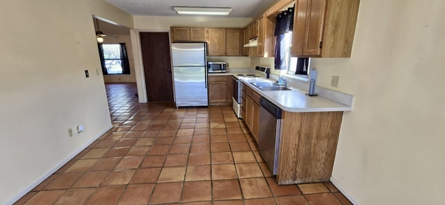 kitchen with light tile patterned floors, stainless steel appliances, light countertops, a sink, and extractor fan