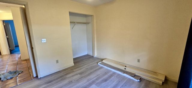 unfurnished bedroom featuring a closet, baseboards, and wood finished floors