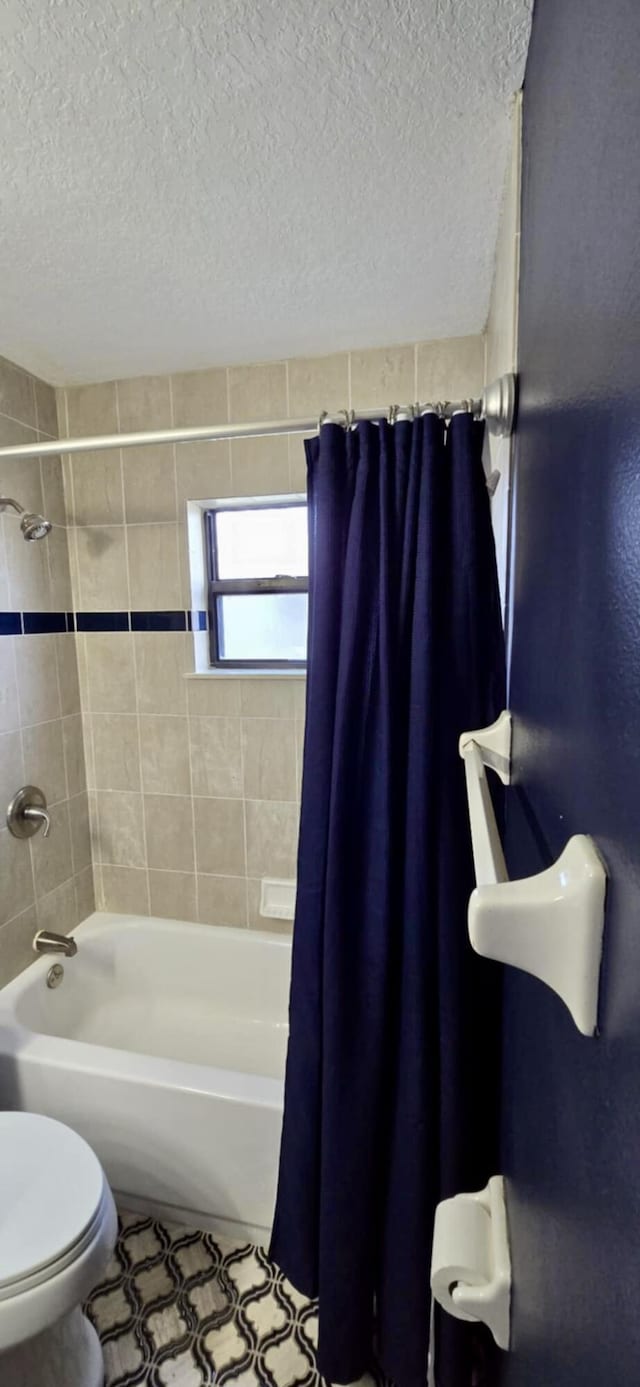 full bath featuring a textured ceiling, tile patterned flooring, toilet, and shower / bathtub combination with curtain