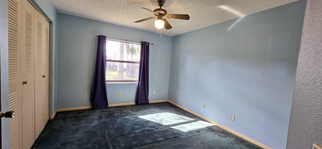 unfurnished bedroom featuring a closet, dark carpet, a textured ceiling, and baseboards