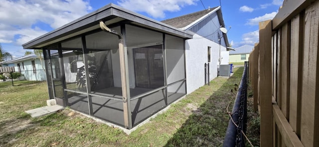 5724 SE Collins Ave, Stuart, FL 34997 - rear view of house with a sunroom, a yard, roof with shingles, stucco siding, and central AC unit
