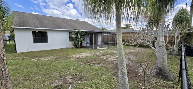 back of house with a fenced backyard, a shingled roof, a sunroom, a lawn, and stucco siding