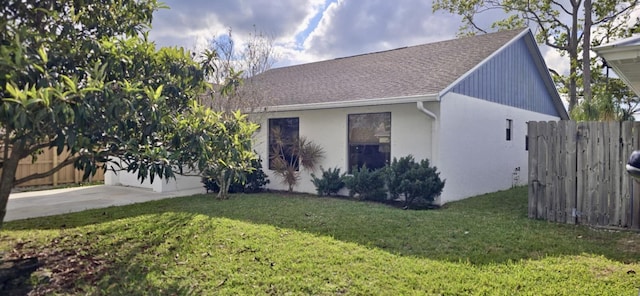 view of front of property featuring a garage, a shingled roof, concrete driveway, fence, and a front lawn