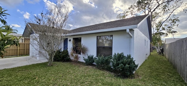 view of front of house featuring concrete driveway, fence, and a front lawn