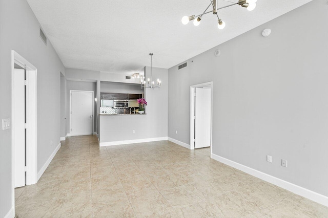 unfurnished living room with a chandelier, visible vents, and baseboards