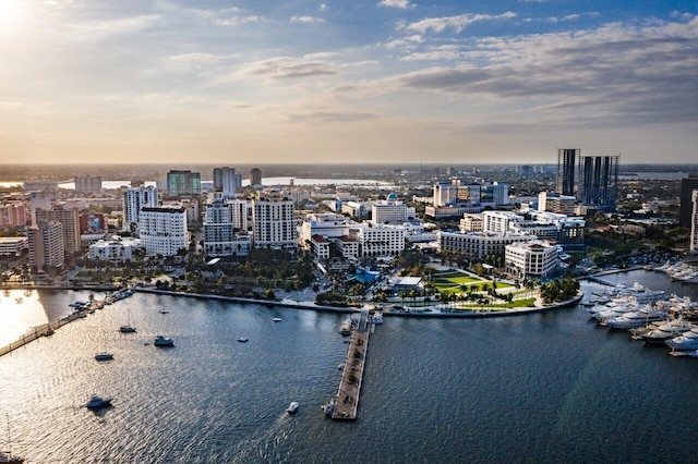 aerial view at dusk featuring a water view and a city view