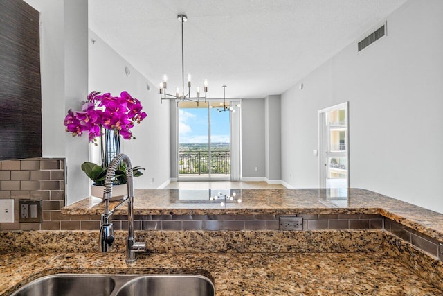 kitchen with a chandelier, a sink, visible vents, hanging light fixtures, and dark countertops