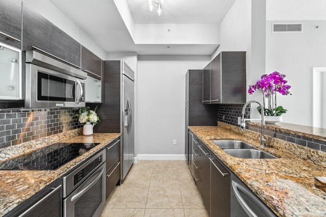 kitchen with a textured ceiling, stainless steel appliances, a sink, visible vents, and tasteful backsplash