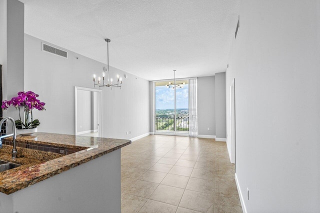 kitchen featuring visible vents, a wall of windows, a textured ceiling, a chandelier, and pendant lighting