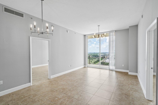 unfurnished dining area featuring visible vents, a chandelier, a wall of windows, and baseboards