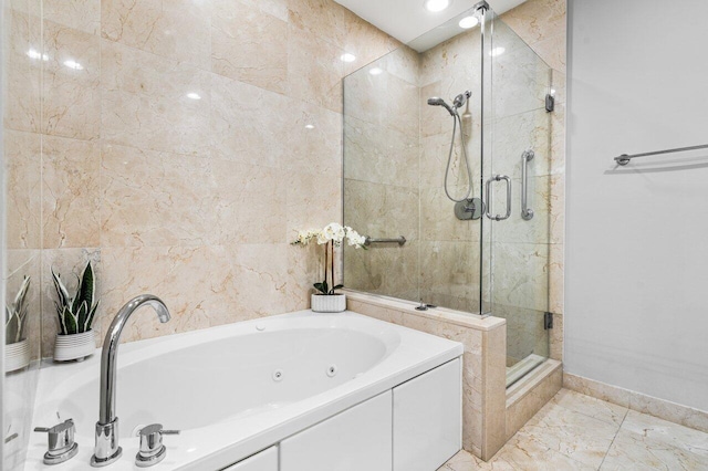 bathroom with a stall shower, baseboards, a tub with jets, marble finish floor, and tile walls