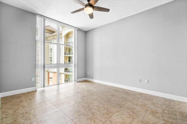 empty room with light tile patterned floors, floor to ceiling windows, baseboards, and a ceiling fan