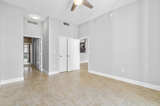 unfurnished room featuring baseboards, visible vents, ceiling fan, and a textured ceiling