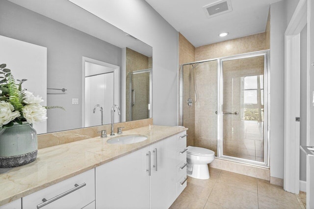 bathroom with toilet, vanity, visible vents, a shower stall, and tile patterned floors