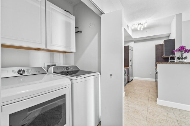 laundry room with a textured ceiling, light tile patterned flooring, washing machine and dryer, laundry area, and baseboards