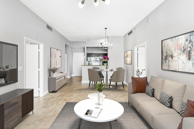 living room featuring baseboards, visible vents, and a notable chandelier