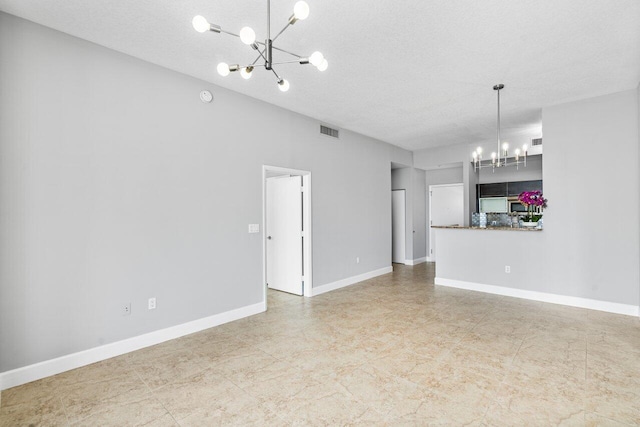 unfurnished living room with a textured ceiling, baseboards, visible vents, and a notable chandelier