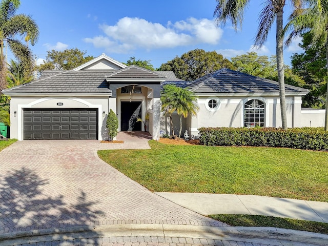 single story home featuring decorative driveway, a front lawn, an attached garage, and stucco siding