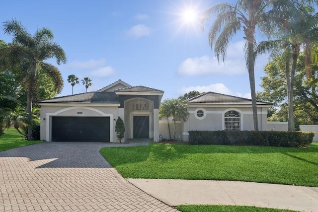 mediterranean / spanish-style home with a front lawn, decorative driveway, a garage, and stucco siding