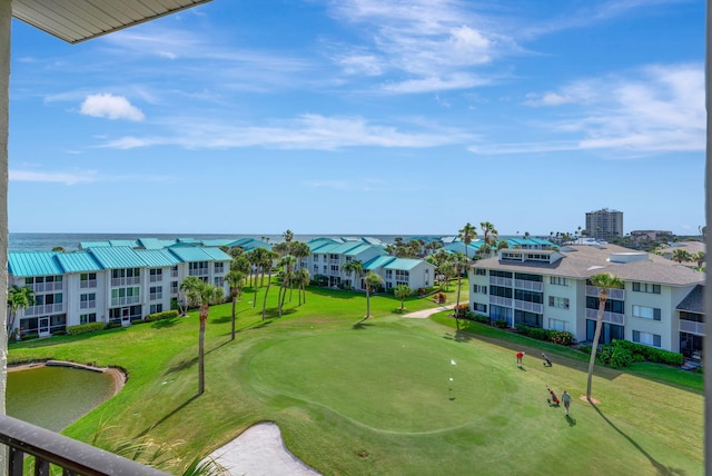 view of community featuring view of golf course and a yard