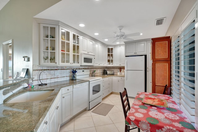 kitchen featuring light tile patterned floors, tasteful backsplash, visible vents, a sink, and white appliances