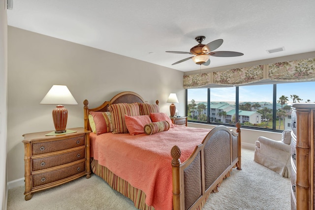 bedroom with light carpet, ceiling fan, visible vents, and baseboards