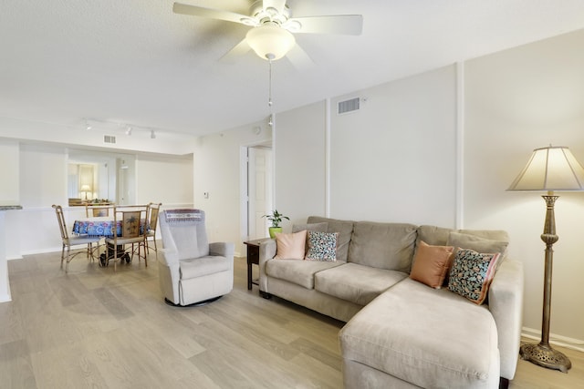 living room featuring light wood finished floors, visible vents, a ceiling fan, and rail lighting