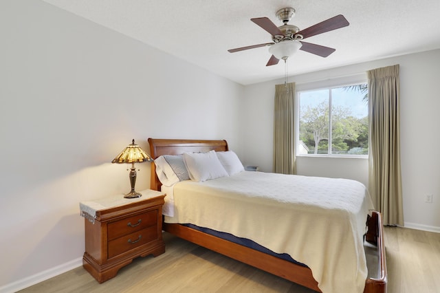 bedroom featuring a ceiling fan, baseboards, and light wood finished floors