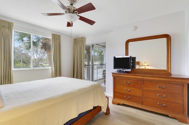 bedroom featuring access to exterior, multiple windows, light wood finished floors, and a ceiling fan