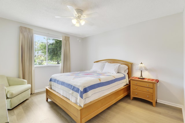 bedroom with baseboards, ceiling fan, light wood-style flooring, and a textured ceiling