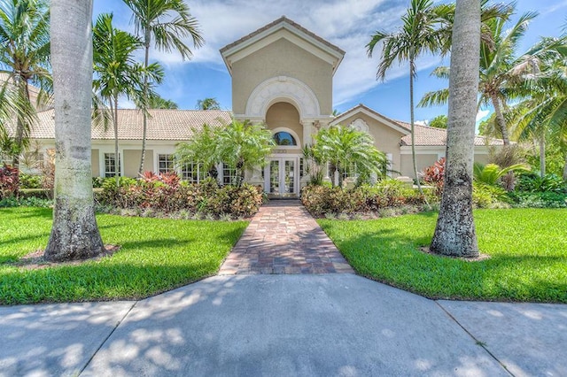 mediterranean / spanish-style home with french doors, a tiled roof, a front lawn, and stucco siding