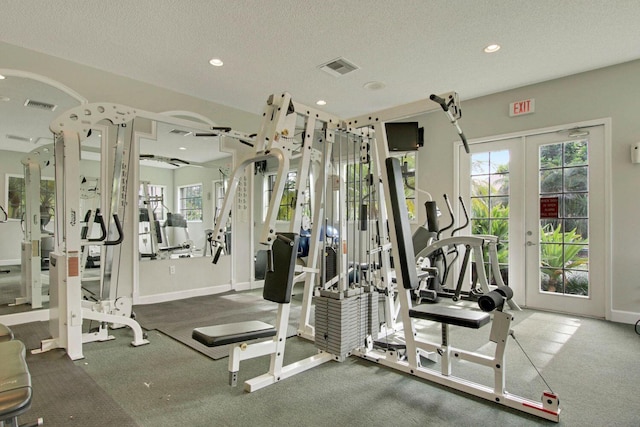 exercise room with a textured ceiling, french doors, visible vents, and a healthy amount of sunlight