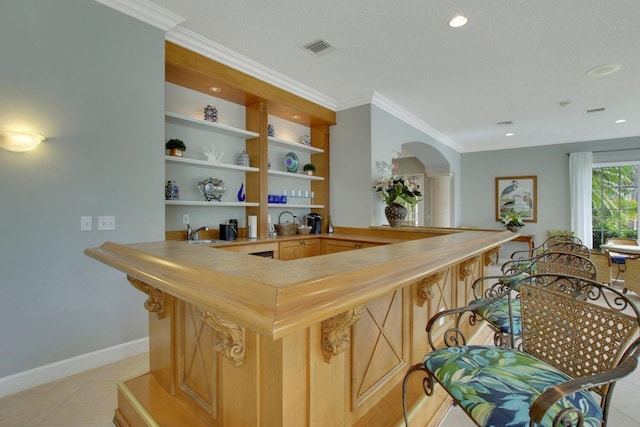 bar featuring baseboards, arched walkways, visible vents, ornamental molding, and wet bar