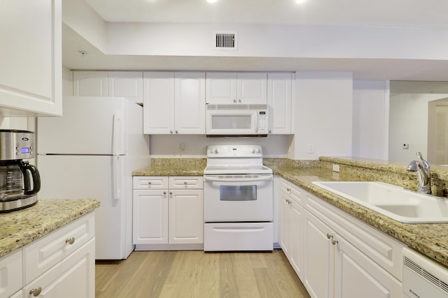 kitchen with light wood-style flooring, white appliances, a sink, visible vents, and white cabinets