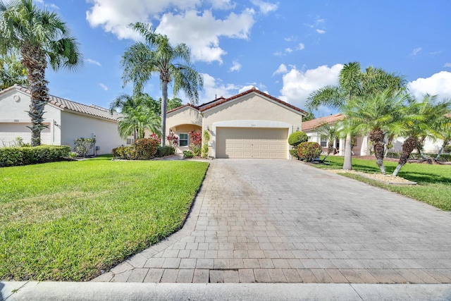 mediterranean / spanish home with a garage, a tile roof, decorative driveway, stucco siding, and a front lawn