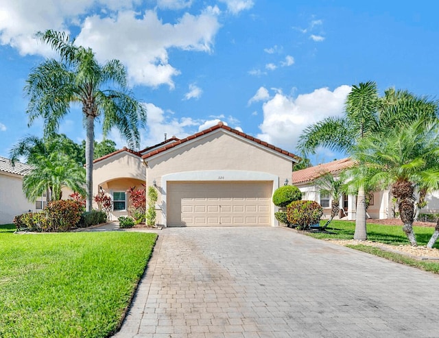 320 NW Alana Ave, Port Saint Lucie, FL 34986 - mediterranean / spanish-style house featuring stucco siding, an attached garage, decorative driveway, and a front yard