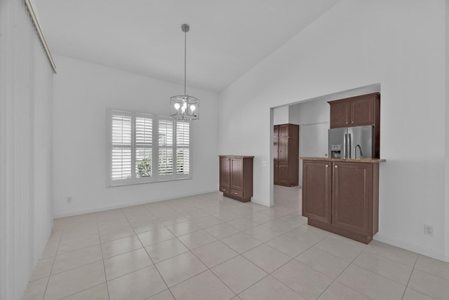 interior space featuring baseboards, high vaulted ceiling, a notable chandelier, and light tile patterned flooring