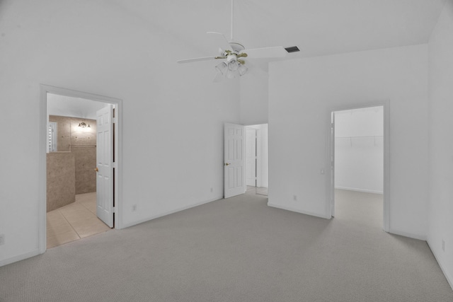 unfurnished bedroom featuring visible vents, ensuite bath, carpet, a spacious closet, and high vaulted ceiling