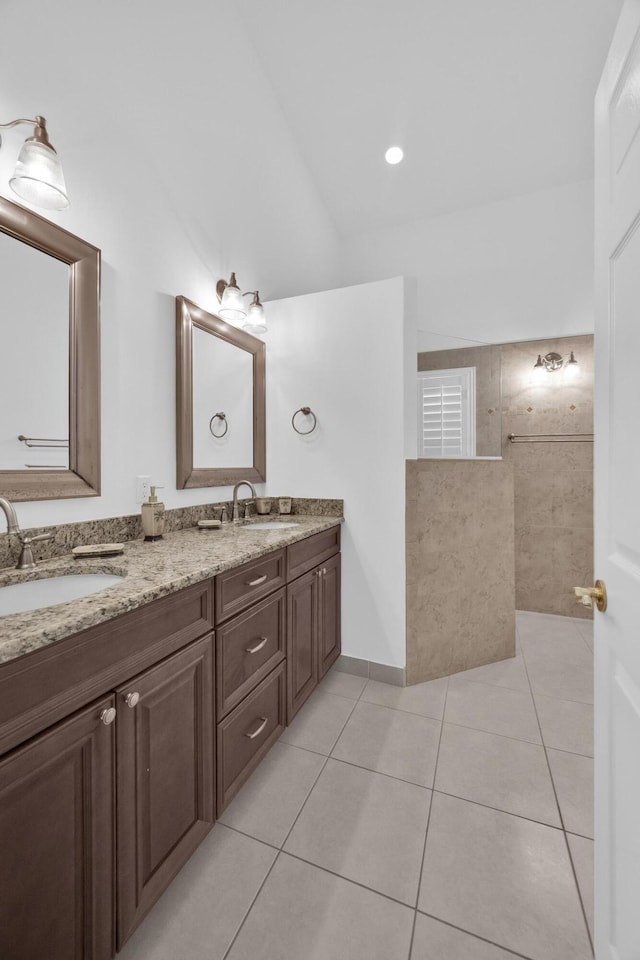 bathroom with double vanity, lofted ceiling, a sink, and tile patterned floors