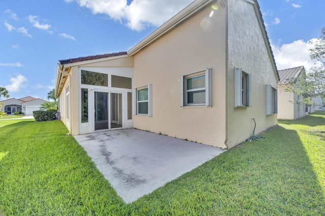 back of house with a yard, a patio, and stucco siding