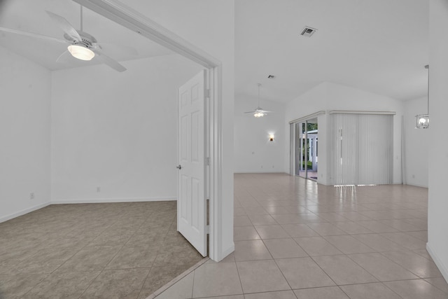 unfurnished living room featuring baseboards, visible vents, a ceiling fan, vaulted ceiling, and light tile patterned flooring