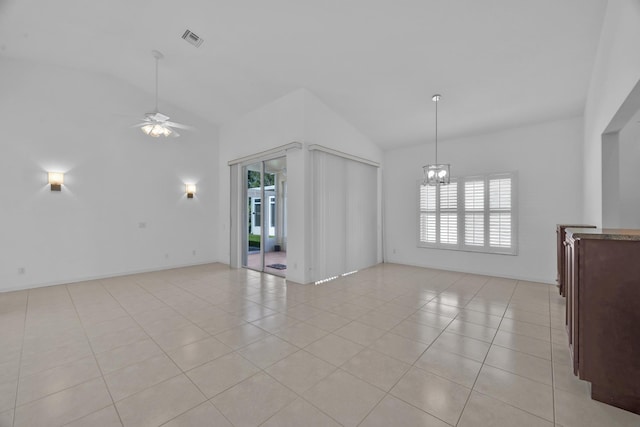 unfurnished living room featuring ceiling fan with notable chandelier, visible vents, vaulted ceiling, and light tile patterned flooring