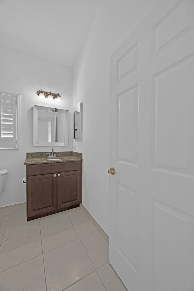 half bathroom with toilet, tile patterned flooring, and vanity